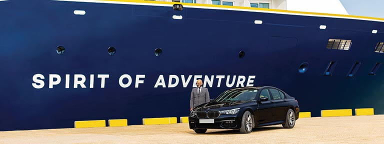 A chauffeur service car and driver standing next to Spirit of Adventure in port